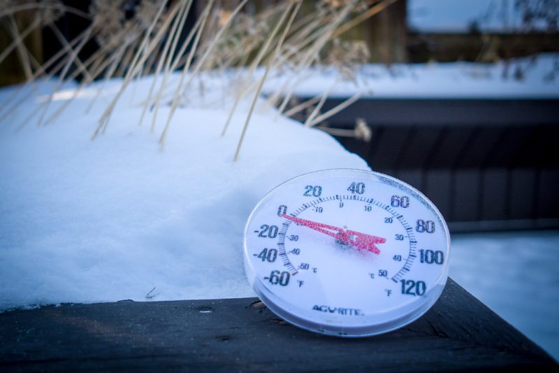 An outdoor thermometer sitting in snow reading below freezing